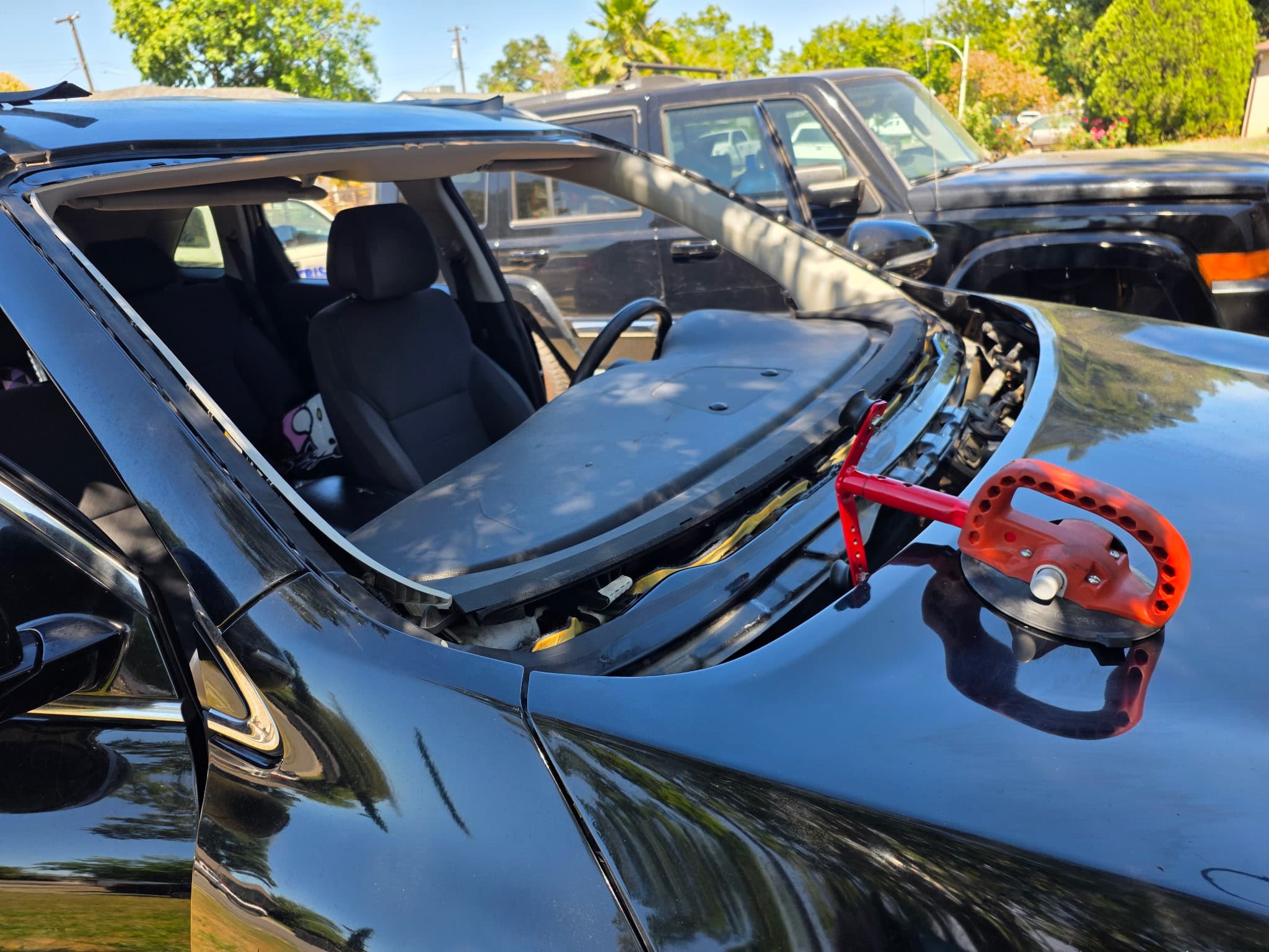 Black SUV windshield install with red suction tool